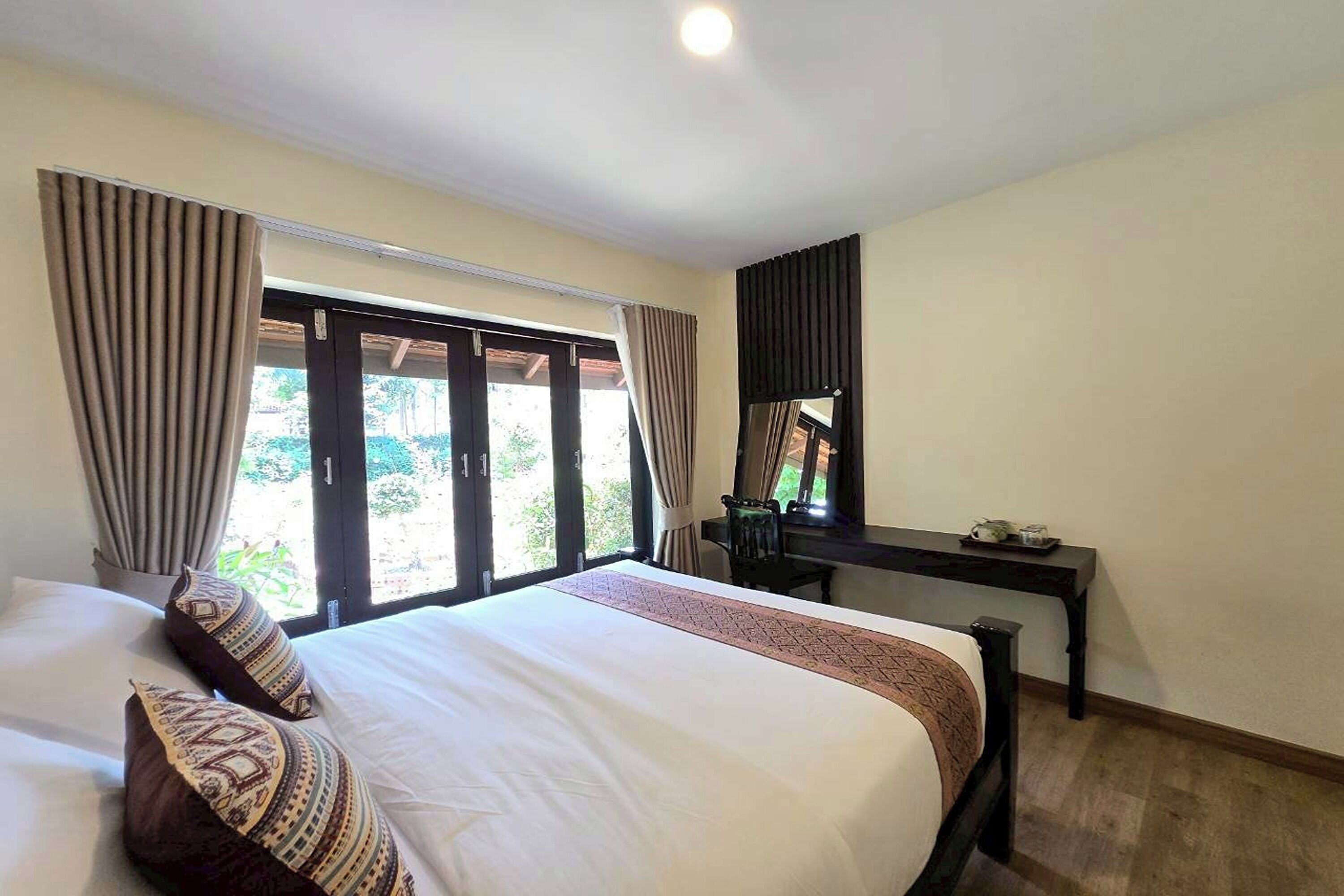 Una habitación de hotel con cama, escritorio y ventana con cortinas.