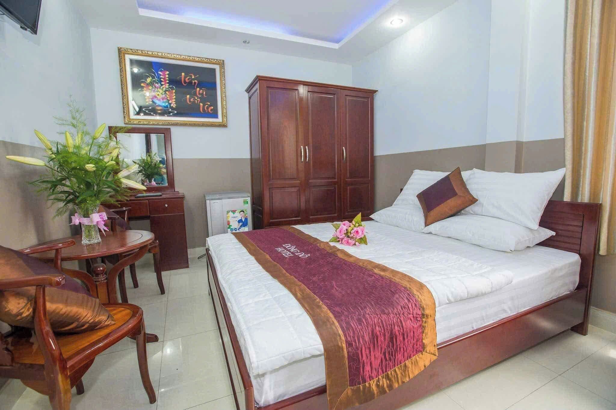 A hotel room with a bed, wooden furniture, a desk, and a mirror.