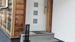 A wooden exterior with a white door, a welcome sign, and a concrete staircase leading to the entrance.