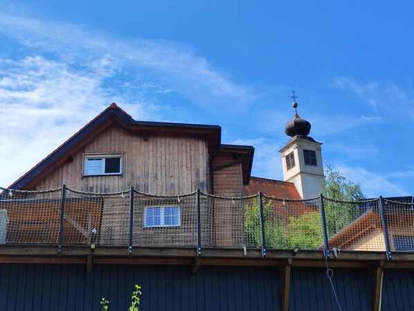A wooden building with a bell tower, a fenced area, and a clear sky.