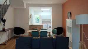 A modern living room with a sofa, chairs, a dining table, and a kitchen in the background. - Maison 5 ch Wifi Exterieur (Faches-Thumesnil)