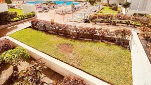 Une cour d’hôtel avec une piscine, des chaises longues et un jardin bien entretenu.