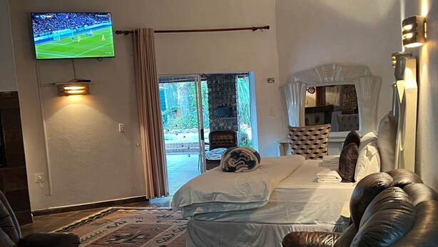 Une chambre d’hôtel avec un lit, un canapé en cuir, une télévision et une vue sur l’extérieur.