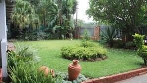 Un jardin bien entretenu, avec une variété de plantes, un grand pot en terre cuite et une bordure en briques.