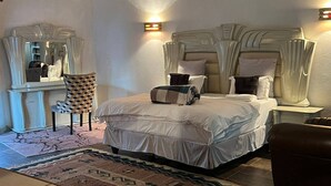 Une chambre à coucher avec un grand lit, une chaise, un bureau et un miroir.