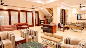 A spacious hotel lobby with multiple seating areas, a reception desk, and a staircase leading to upper floors. - asar Suites GK1 By Orion Hotels (New Delhi)