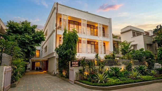A modern building with a sign reading 'asar suites,' surrounded by lush greenery and a paved entrance. - asar Suites GK1 By Orion Hotels (New Delhi)