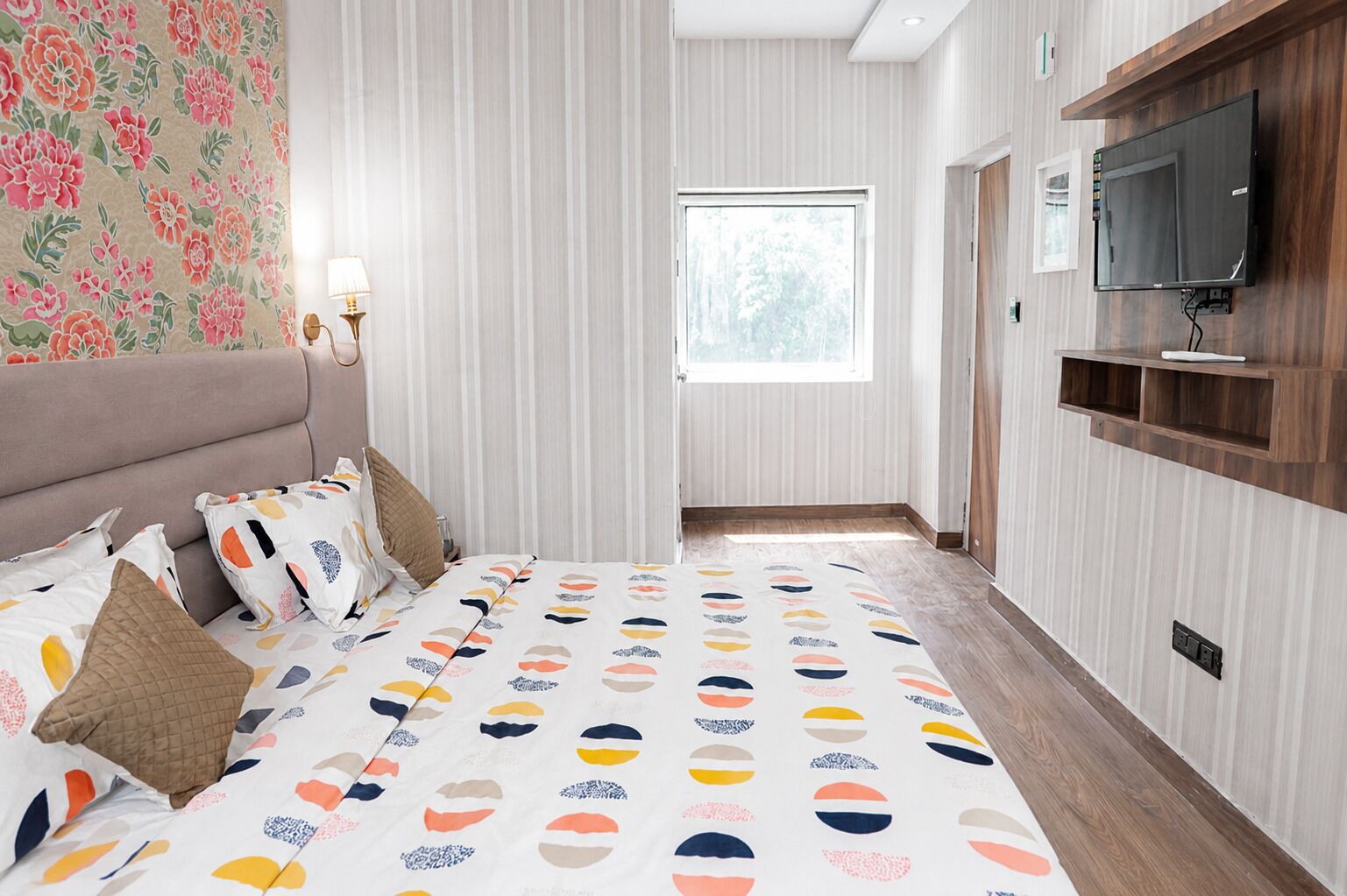 A bedroom with a bed, pillows, a TV, and a window.