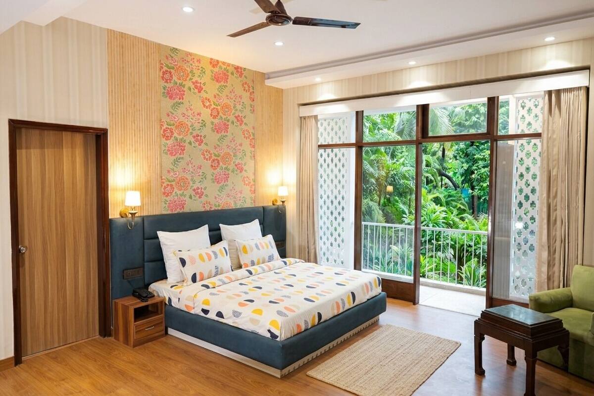 A bedroom with a bed, bedside tables, a ceiling fan, and a large window with a view of greenery.