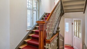 Un escalier avec des rampes en bois et des marches recouvertes d’une moquette rouge.