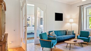 Un salon moderne avec un canapé, des fauteuils, une table basse et un téléviseur.