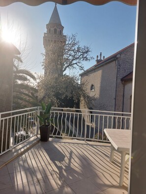 Ein Balkon mit weißer Brüstung, einem Blumentopf und einem Tisch.
