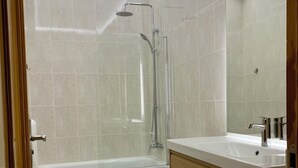 Et moderne badeværelse med brusebad, toilet og vaskebord.