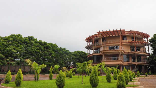 A multi-story building with balconies, surrounded by well-maintained greenery and trees.