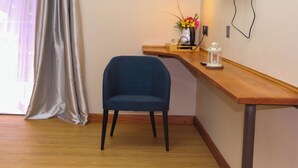 A room with a wooden desk, a blue chair, a vase with flowers, and a white lantern.