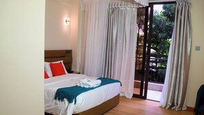 A bedroom with a bed, a nightstand, a chair, and a sliding glass door leading to an outdoor area.