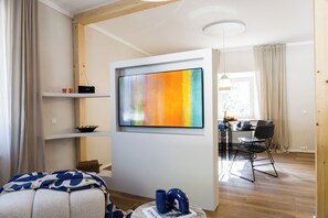 A modern room with a flat-screen TV, a dining area with a table and chairs, and a cozy seating area with a sofa and cushions. - MAEXPASTRY - the loft apartment (Bergen)