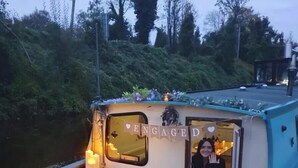 A boat with a small deck area, a bench, and a table with candles and flowers.