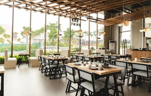 A restaurant with multiple tables, chairs, and hanging lights.