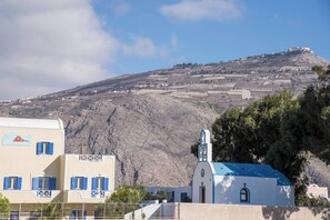 A coastal village with buildings, a church, and a hill in the background. - Apartment Garden View, 3 guests in a family hotel (Perivolos)