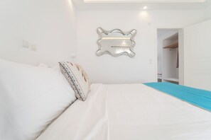 A bedroom with a bed, a wall-mounted mirror, and a door leading to a closet. - Apartment Garden View, 3 guests in a family hotel (Perivolos)
