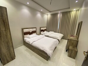 A hotel room with two beds, a wooden headboard, a small wooden nightstand, and a mirror. - Al Salam Three Bedrooms Hall Kitchen j12 (Jeddah)