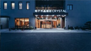 En hotelindgang med en glasfacade, et navneskilt og et godt oplyst område.