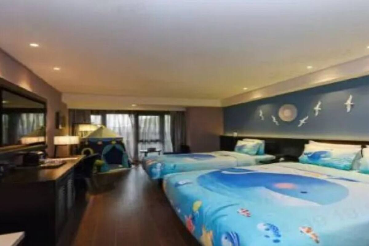 Habitación de hotel con una cama grande, un escritorio con silla, televisor y ventana con cortinas.