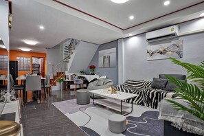 Ein modernes Wohnzimmer mit Sofa, Couchtisch und Essbereich.