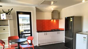 Een kleine keuken met een gasfornuis, een roestvrijstalen koelkast en een backsplash van rode tegels.