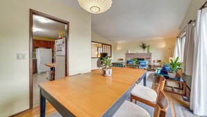 Ein geräumiges Wohnzimmer mit einem Holzesstisch, einem Kamin und einem großen Fenster.