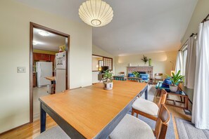 A spacious living room with a wooden dining table, a fireplace, and a large window. - Steps to Great Food, Bus Routes & Light Rail (Seattle)