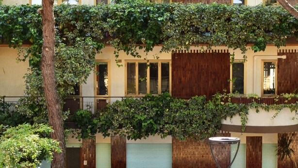 A two-story building with a balcony, a street lamp, and a parked car. - Casa Genziana Sabbiadoro - Terrace - Parking - Air conditioning (Lignano Sabbiadoro)