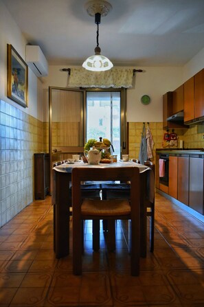 A kitchen with a dining table, chairs, a hanging light fixture, and a window.
