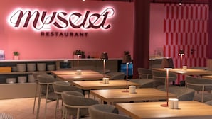 Ravintolan sisustus, jossa on neonvalomainos, pöytiä, tuoleja ja baaritiski.