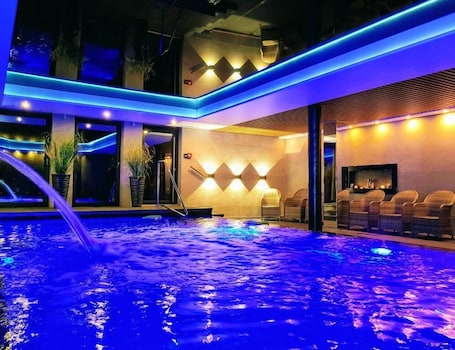 A spa area with a hot tub, seating, and a wall with geometric lighting.