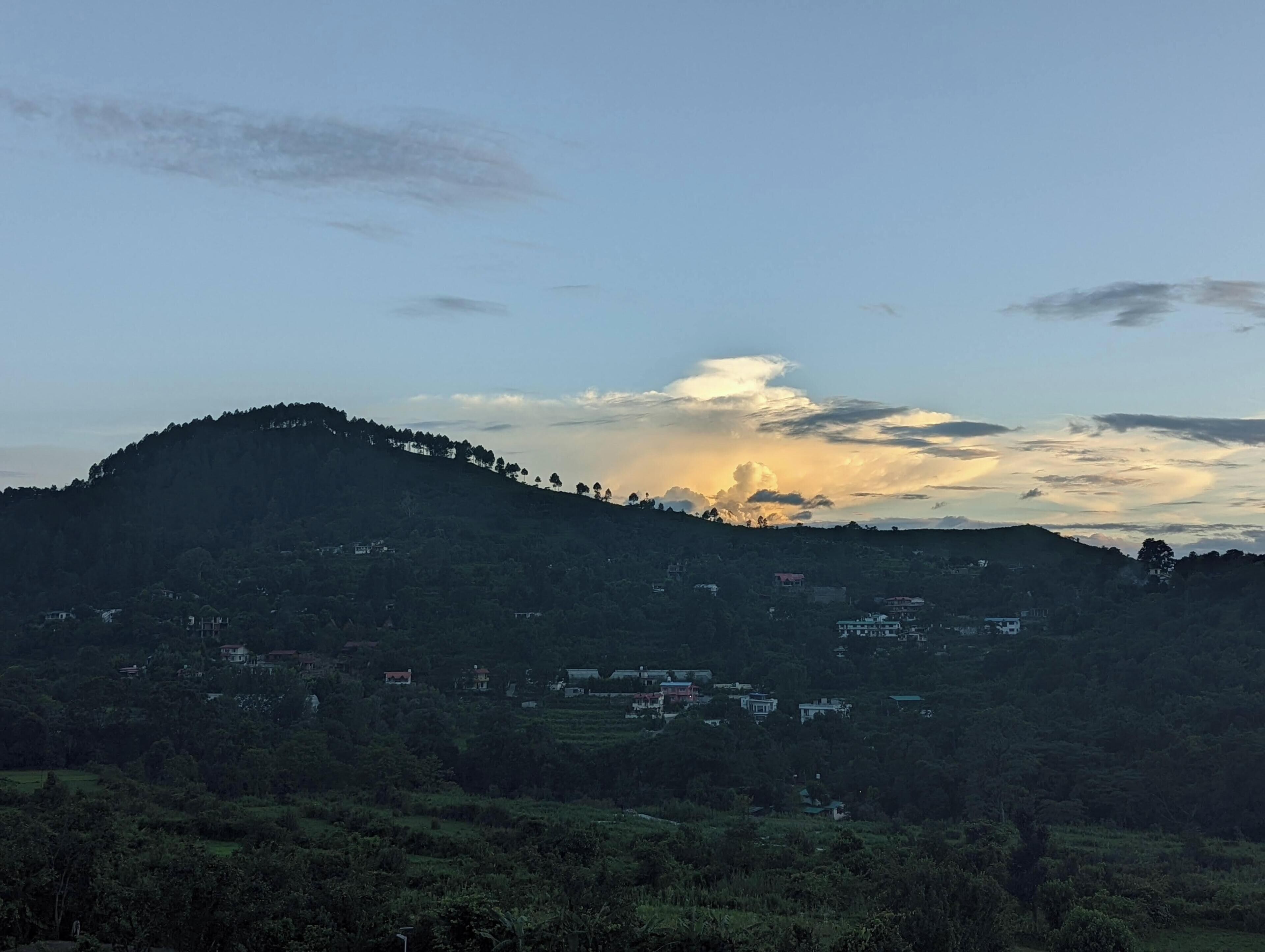 A hilly landscape with scattered buildings, likely a rural or semi-rural area.