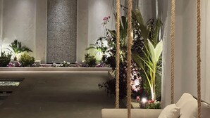A modern outdoor seating area with a sofa and a table, surrounded by plants and a textured wall.