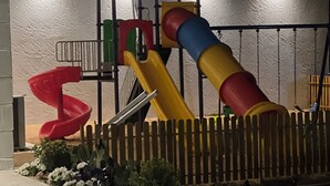 A playground with a slide, a climbing structure, and a small playhouse.