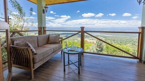 A wooden deck with a sofa and a table, overlooking a scenic landscape.