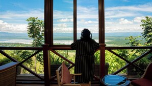 A person standing by a large window overlooking a scenic landscape.