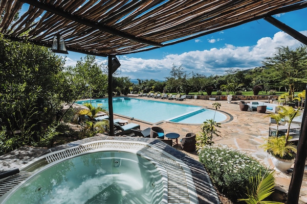 Una piscina al aire libre, sombrillas, sillones reclinables de piscina