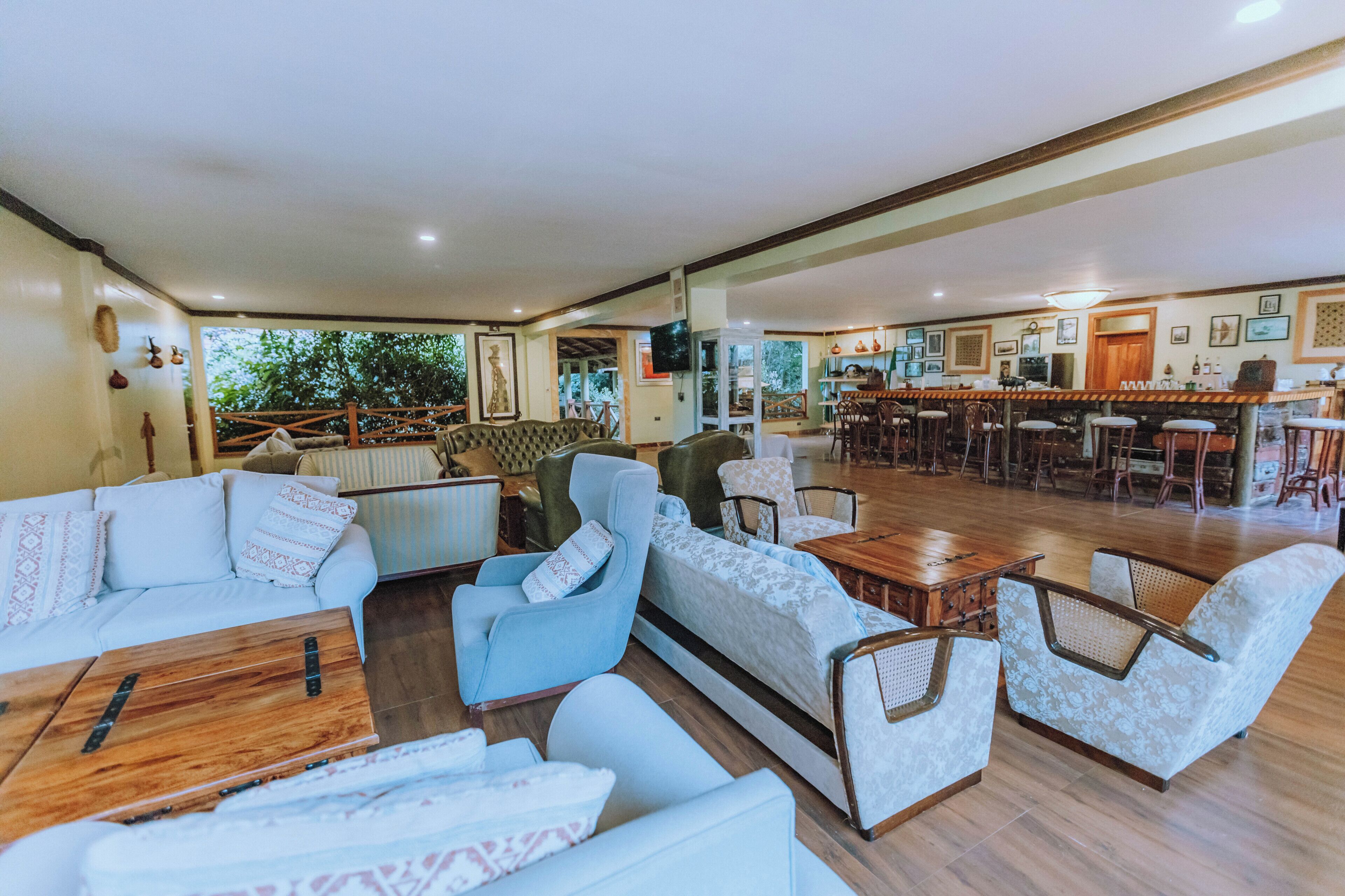 A spacious living area with sofas, armchairs, a wooden coffee table, and a kitchen in the background.