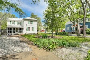 A two-story house with a front porch, a well-maintained garden, and a clear sky.