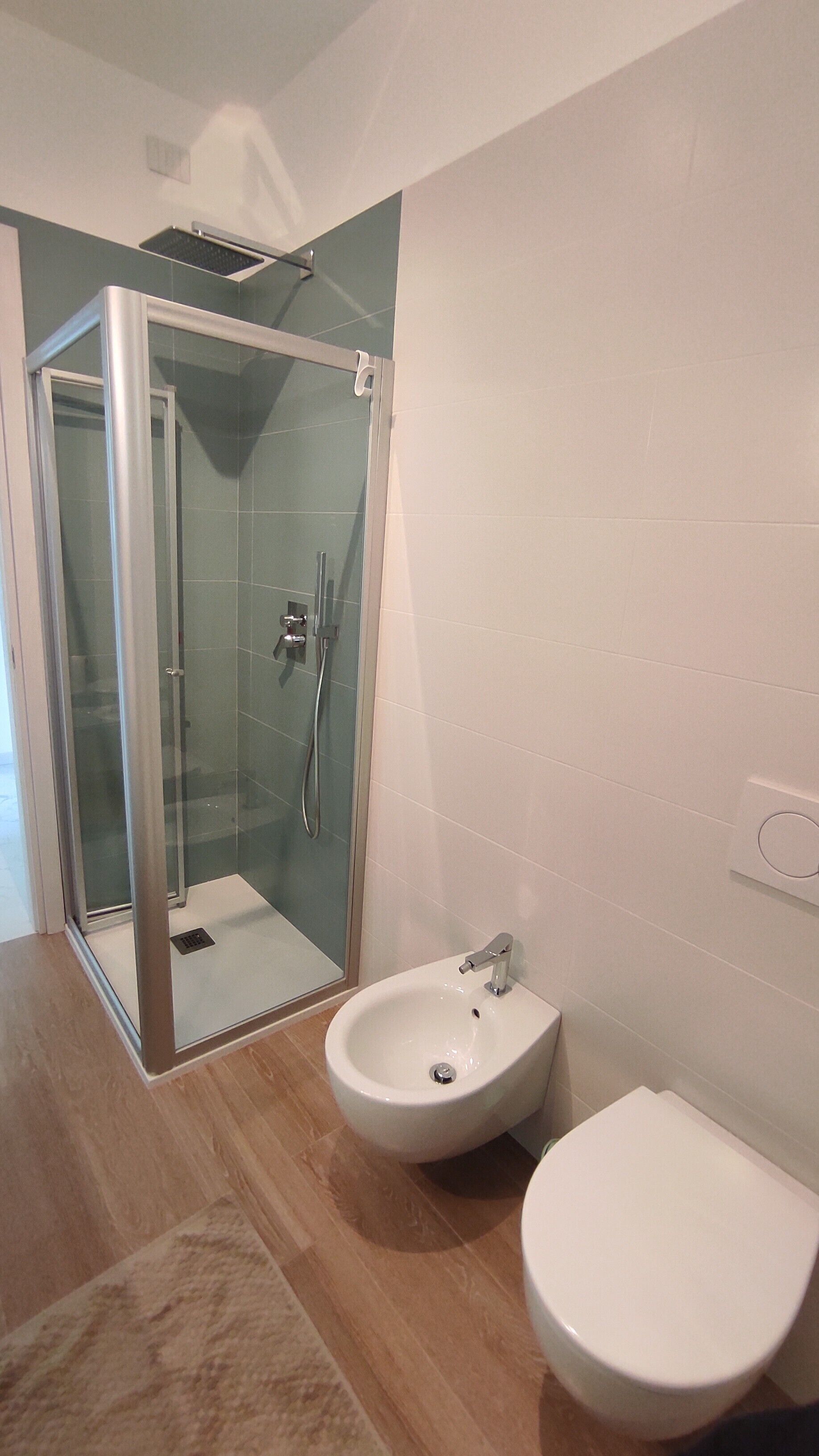 Een badkamer met een douchecabine van glas, een wit wastafel en een toilet.
