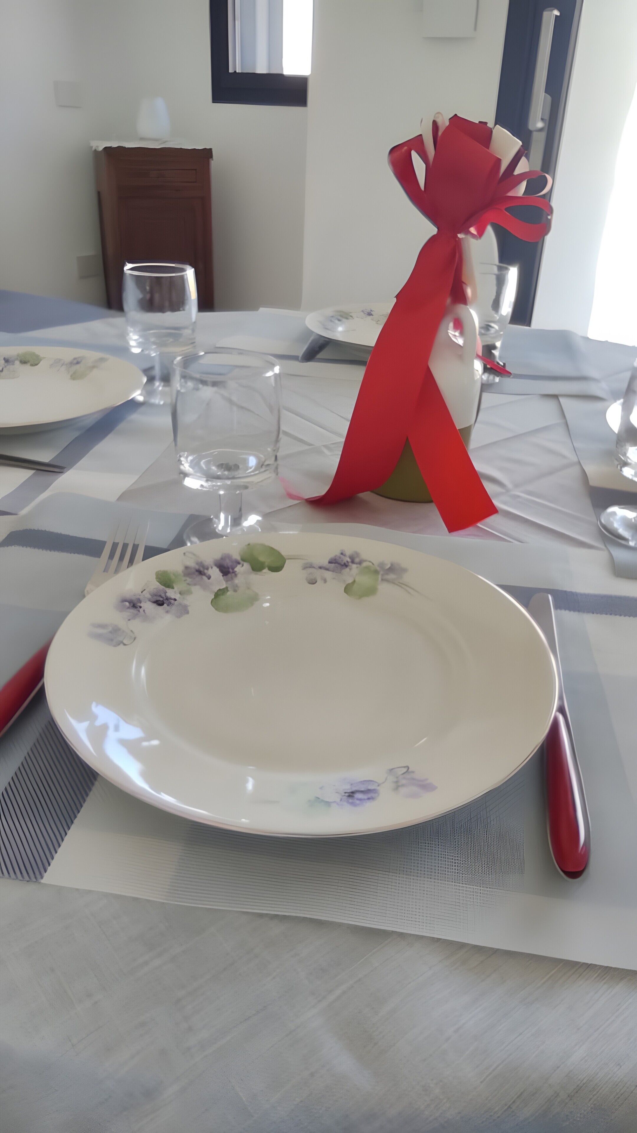 Una mesa de comedor dispuesta con platos, vasos y cubiertos.