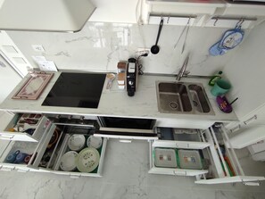 A kitchen with a black stovetop, stainless steel sink, and a white marble countertop. - Holiday Home 'Sun Max - Near The Sea' with Sea View, Wi-Fi and Air Conditioning (San Benedetto del Tronto)
