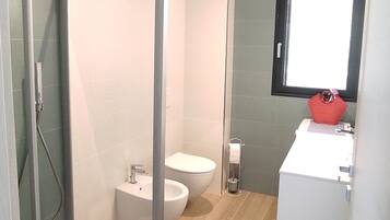 Een moderne badkamer met een douchecabine van glas, een wit wastafelmeubel en een toilet.