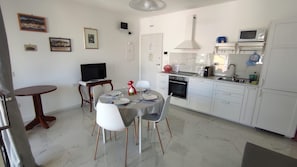 Una cucina moderna con mobili bianchi, un tavolo da pranzo con sedie, una TV e un forno a microonde.