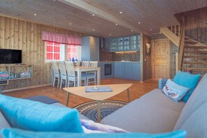 Un intérieur en bois comprenant un canapé, une table à manger, des chaises, un téléviseur et un coin cuisine.